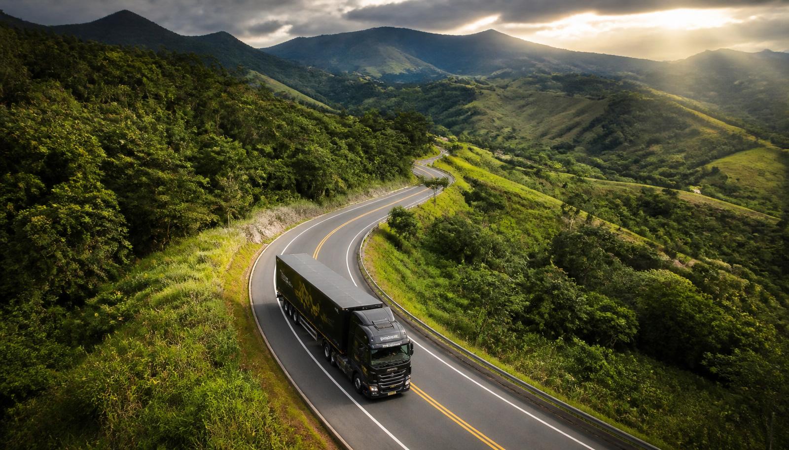 Caminhão da J.C.P Transportes em rodovia entre montanhas